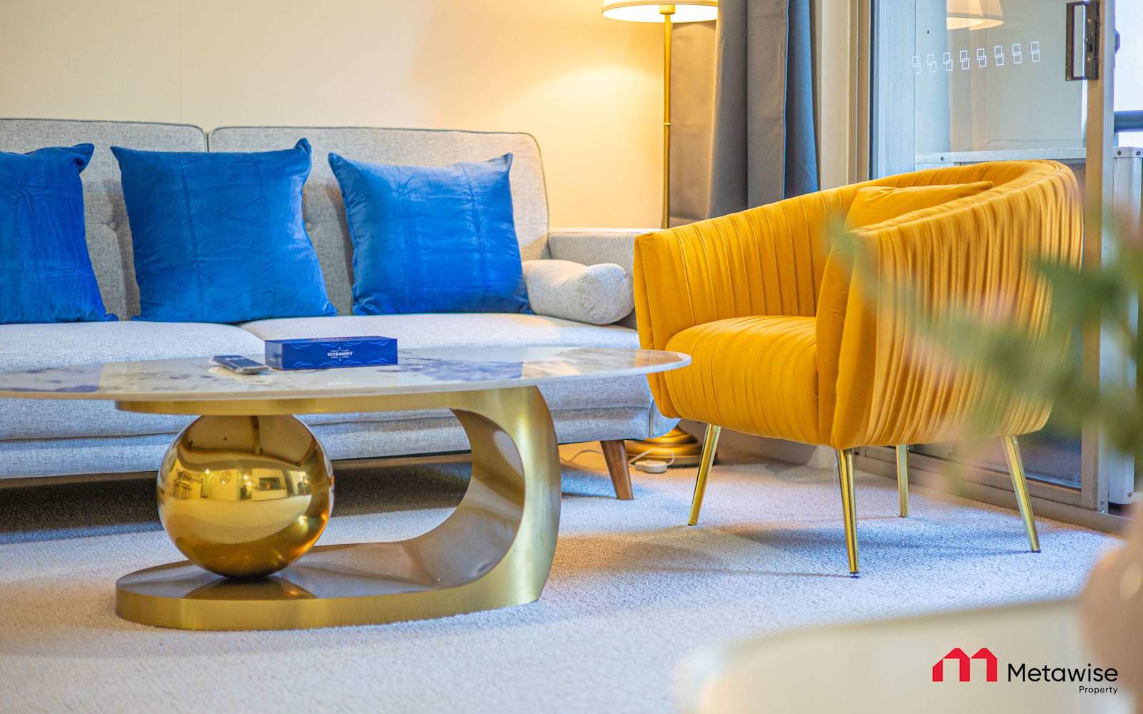 Living room of a MetaWise-managed one-bedroom apartment in Camperdown, blue sofa and a mustard armchair by the window.