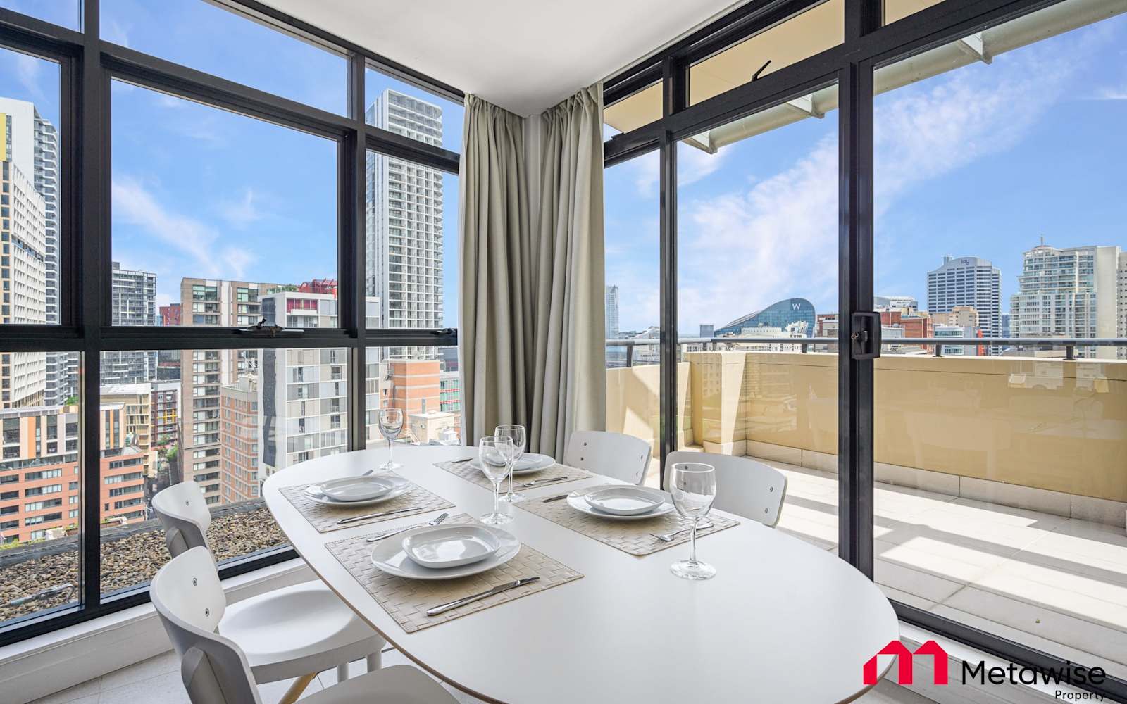 Dining area of a MetaWise-managed two-bedroom apartment in Haymarket, with floor-to-ceiling windows and a balcony over the city.