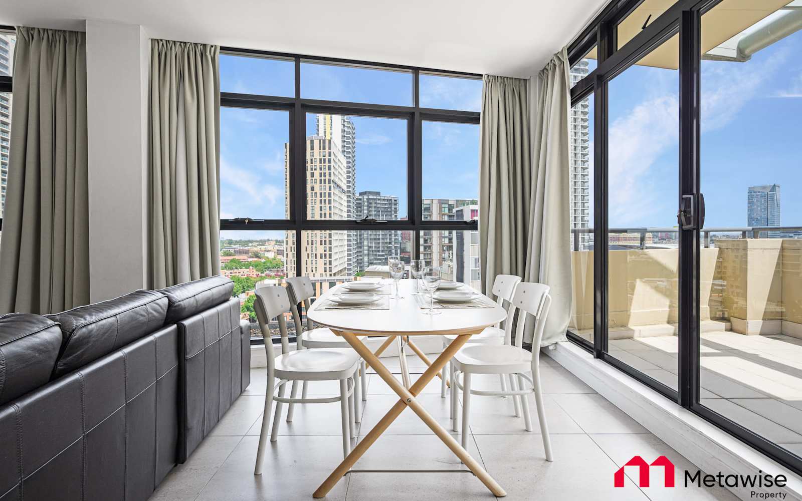Living and dining area of the Haymarket serviced apartment, balcony doors open to the city.