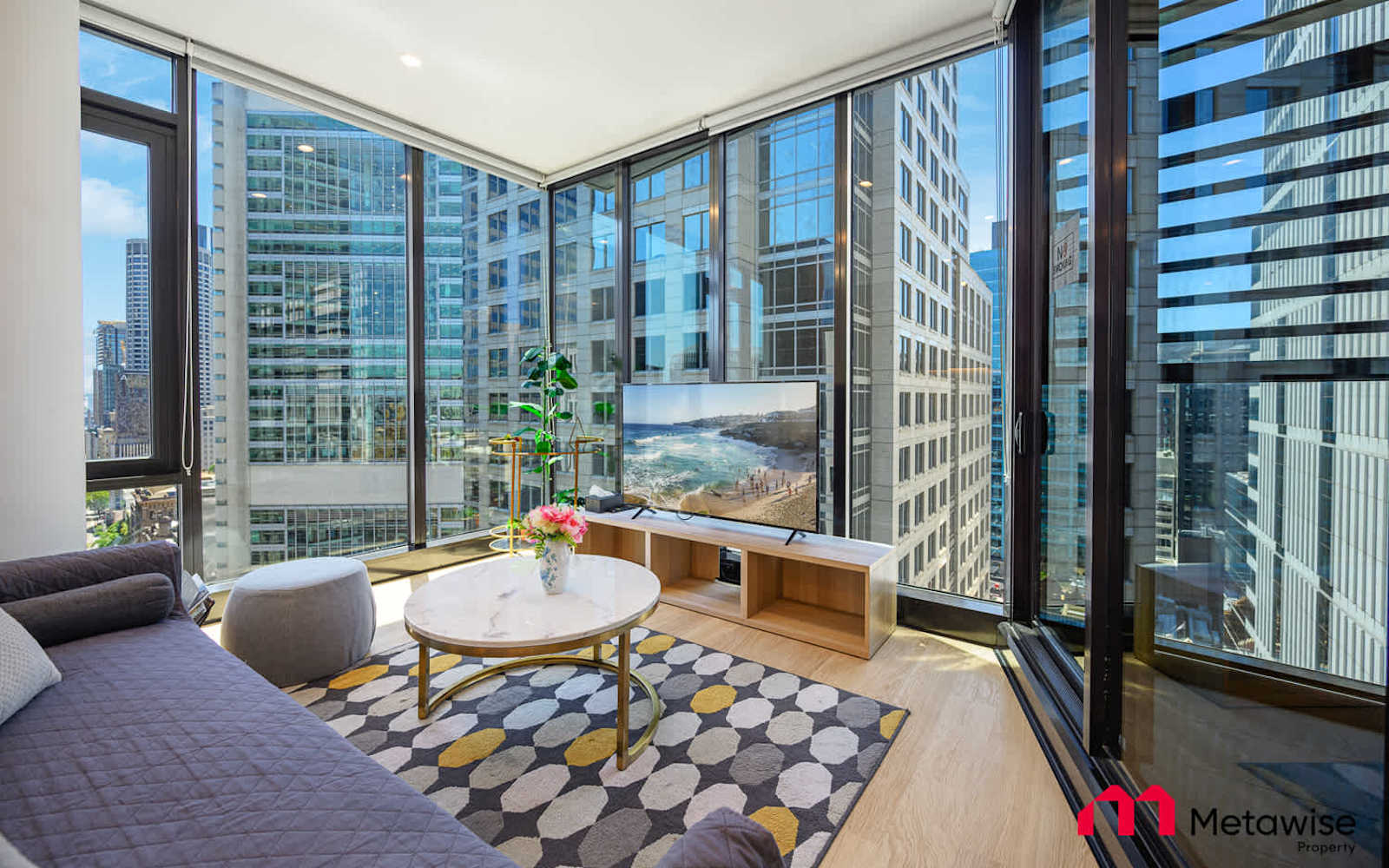 Living room of a MetaWise-managed two-bedroom apartment in the Sydney CBD, floor-to-ceiling windows looking onto the city.